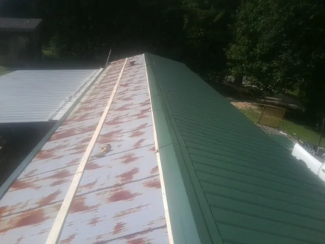 Old rusted panels beside newly installed green metal roofing — Wind Damage Roof Repair by Roofing Brothers in Durkee