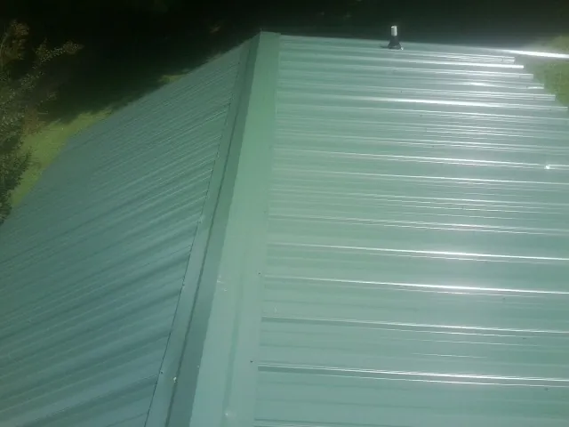 New green metal panels meeting at the ridge of a roof — Flat Roof Repair work by our crew in Durkee