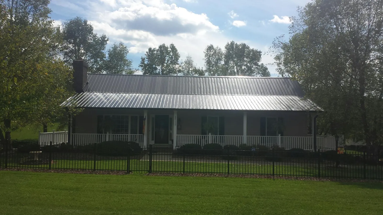 Gray metal roof on a brick ranch with a full width front porch — Gutter Guard Installation work by our crew in Durkee