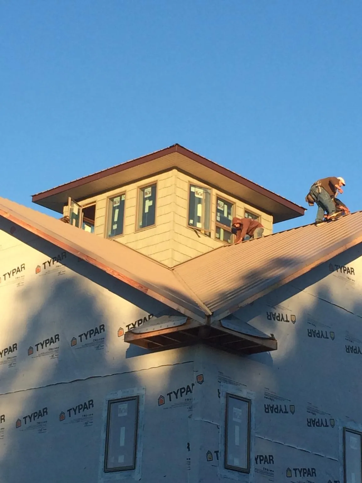 Roofers working around a rooftop cupola on a new metal roof at sunset — Roof Waterproofing in Durkee by Roofing Brothers